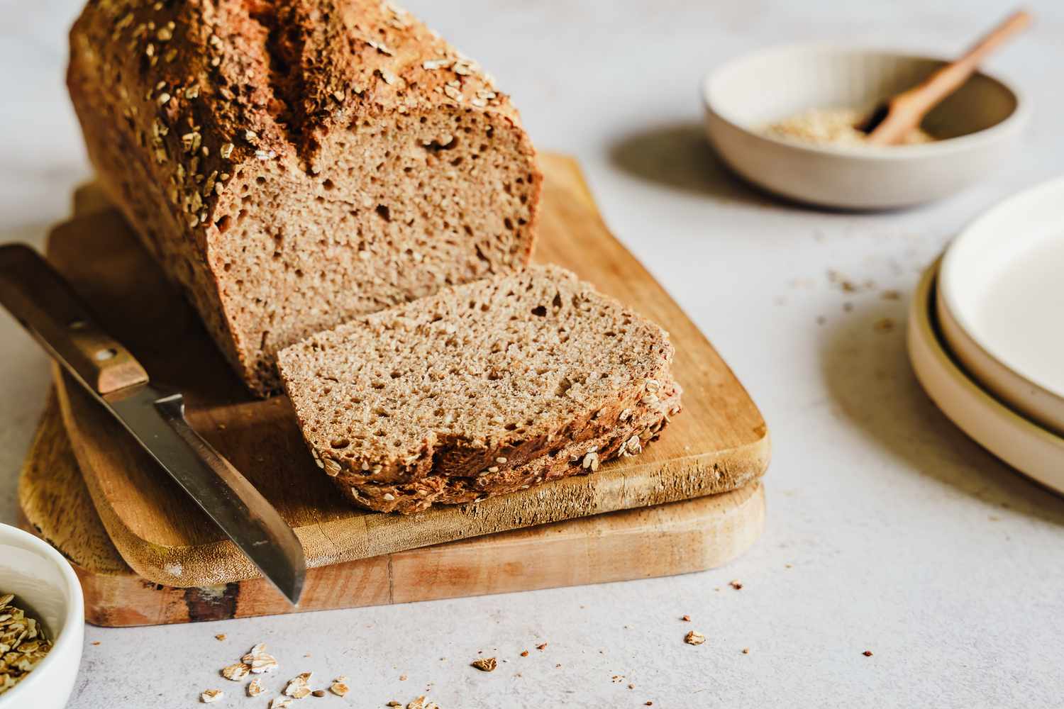 wholewheat bread, slices and the loaf on a wooden board with a knife
