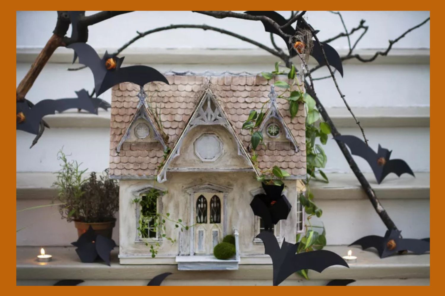 A miniature house decorated with bats and foliage Halloweenthemed decor