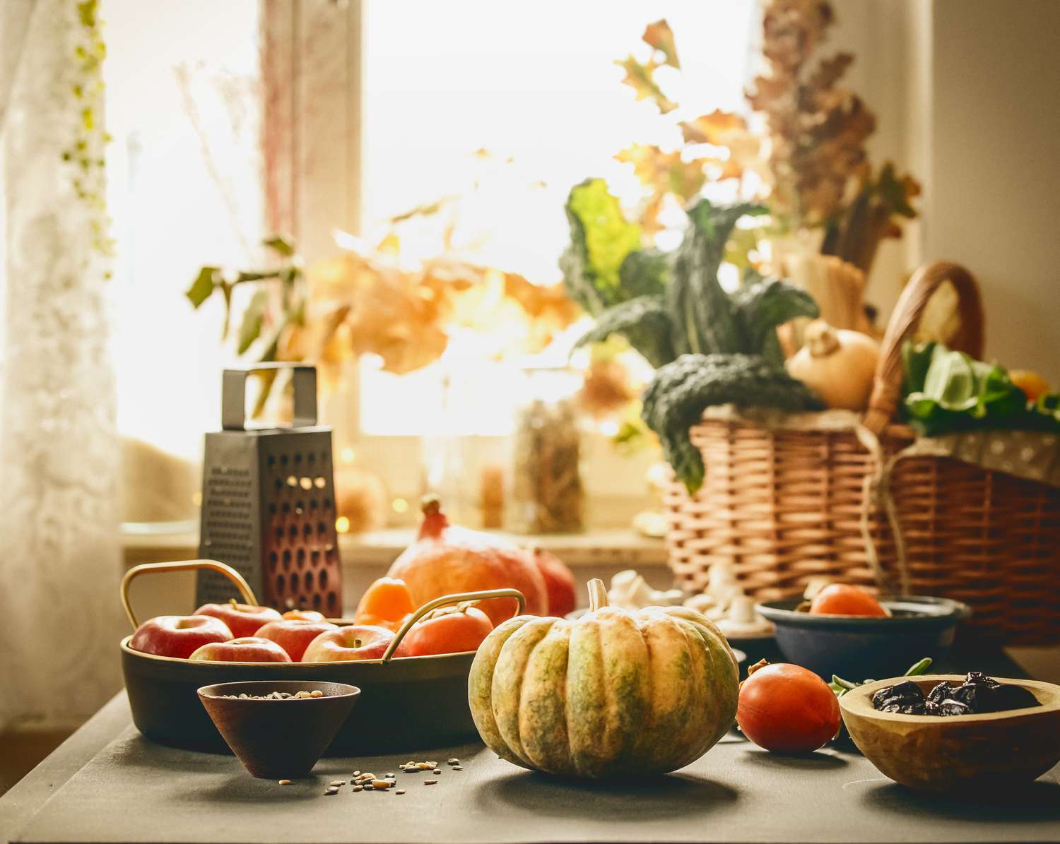 Pumpkin and various seasonal vegatbles and fruits in basket and bowls on kitchen table at window background