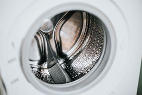 A closeup view of the inside of a washing machine drum highlighting its metallic finish and perforations