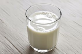 A glass filled with milk placed on a wooden surface