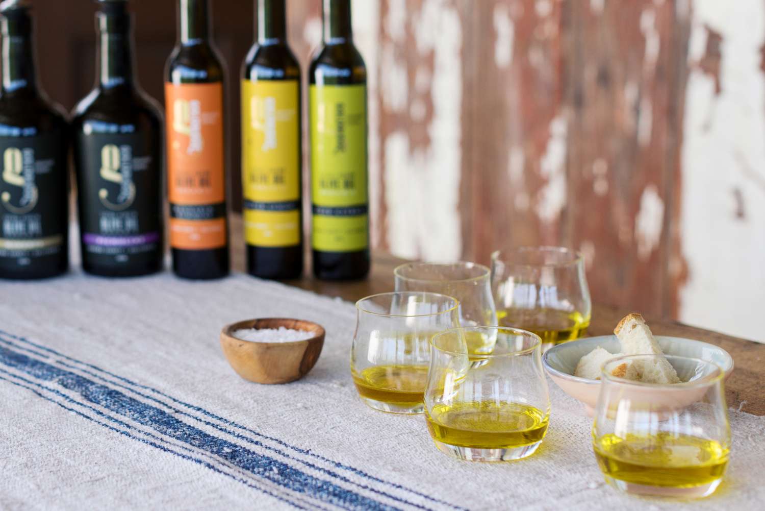 bottles of olive oils and tasting glasses of the oil on rustic white cloth