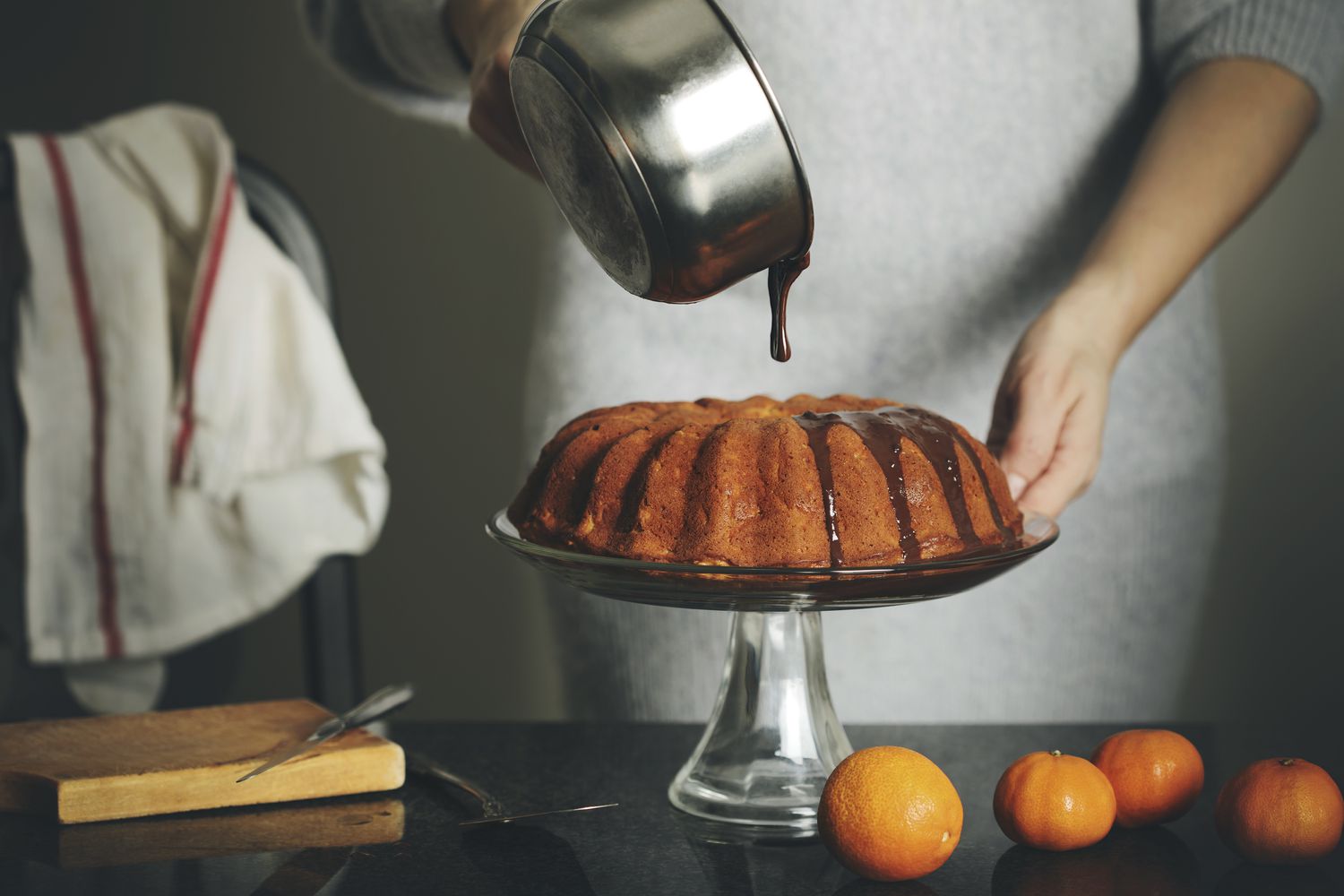 Woman pouring melted chocolate on citrus cake