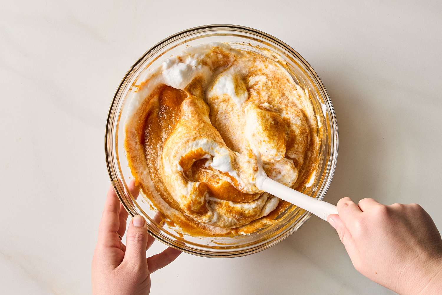 Mixing ingredients in a clear bowl with a spatula