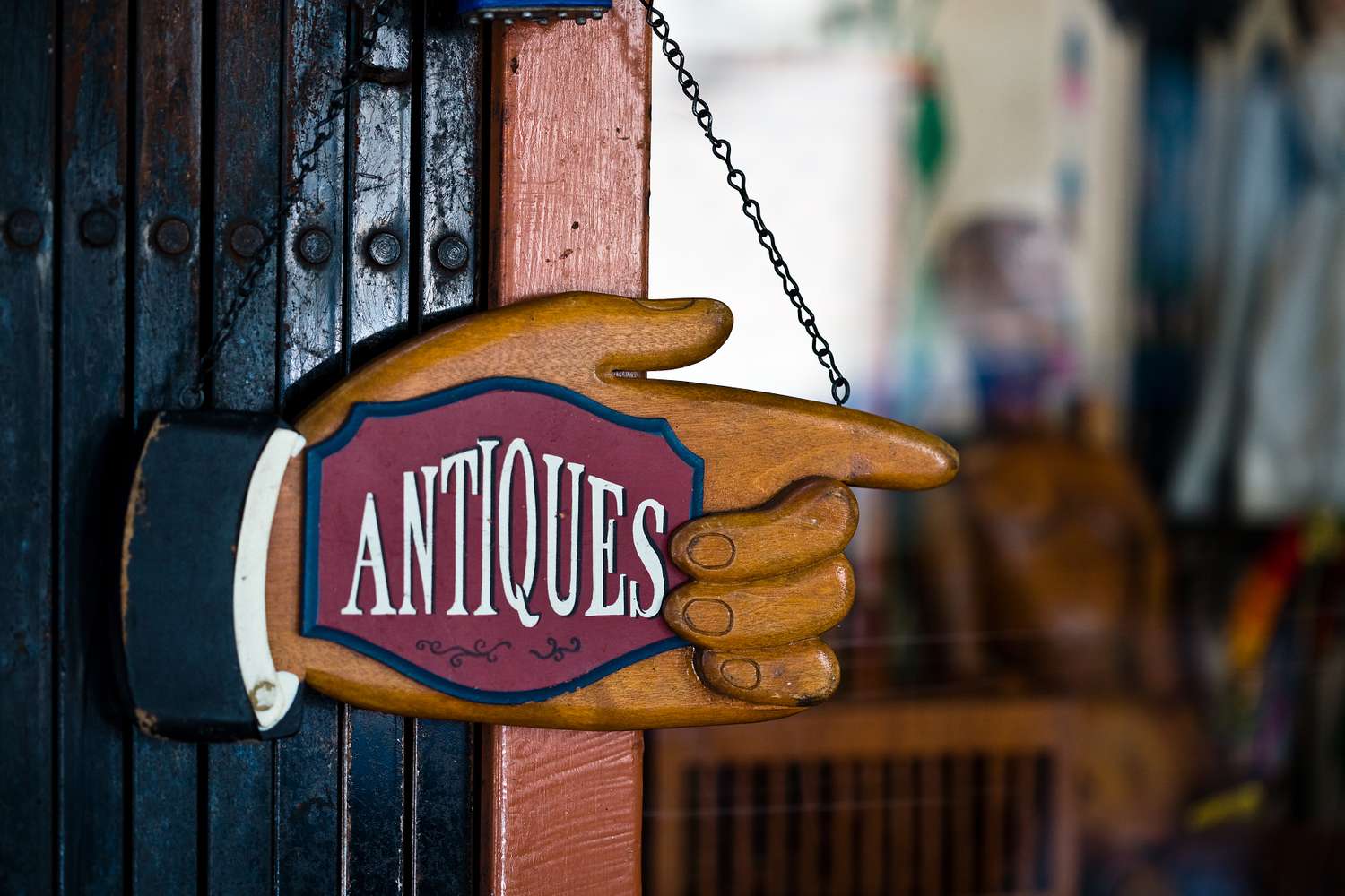 A vintage sign shaped like a pointing hand labeled ANTIQUES mounted on a doorway