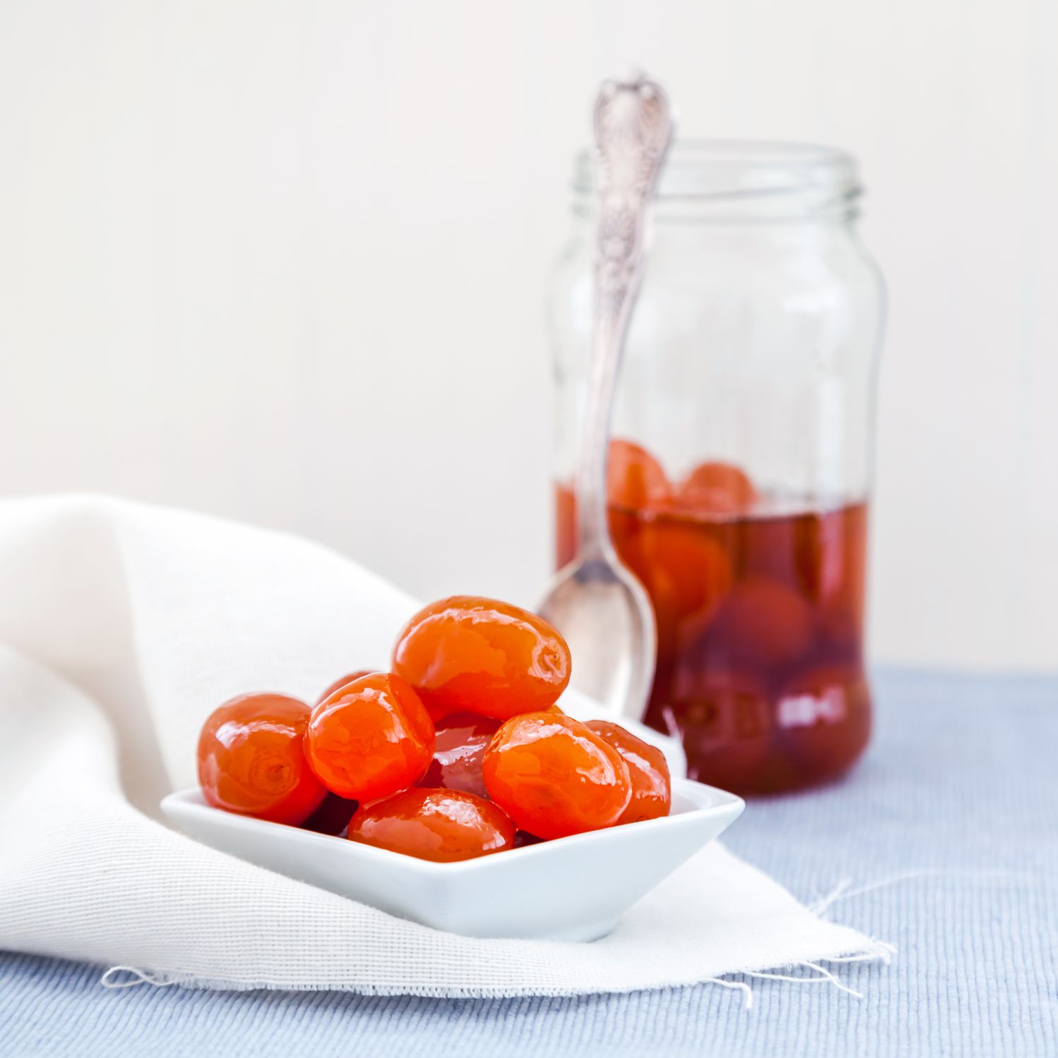 candied kumquats in dish with spoon and jar