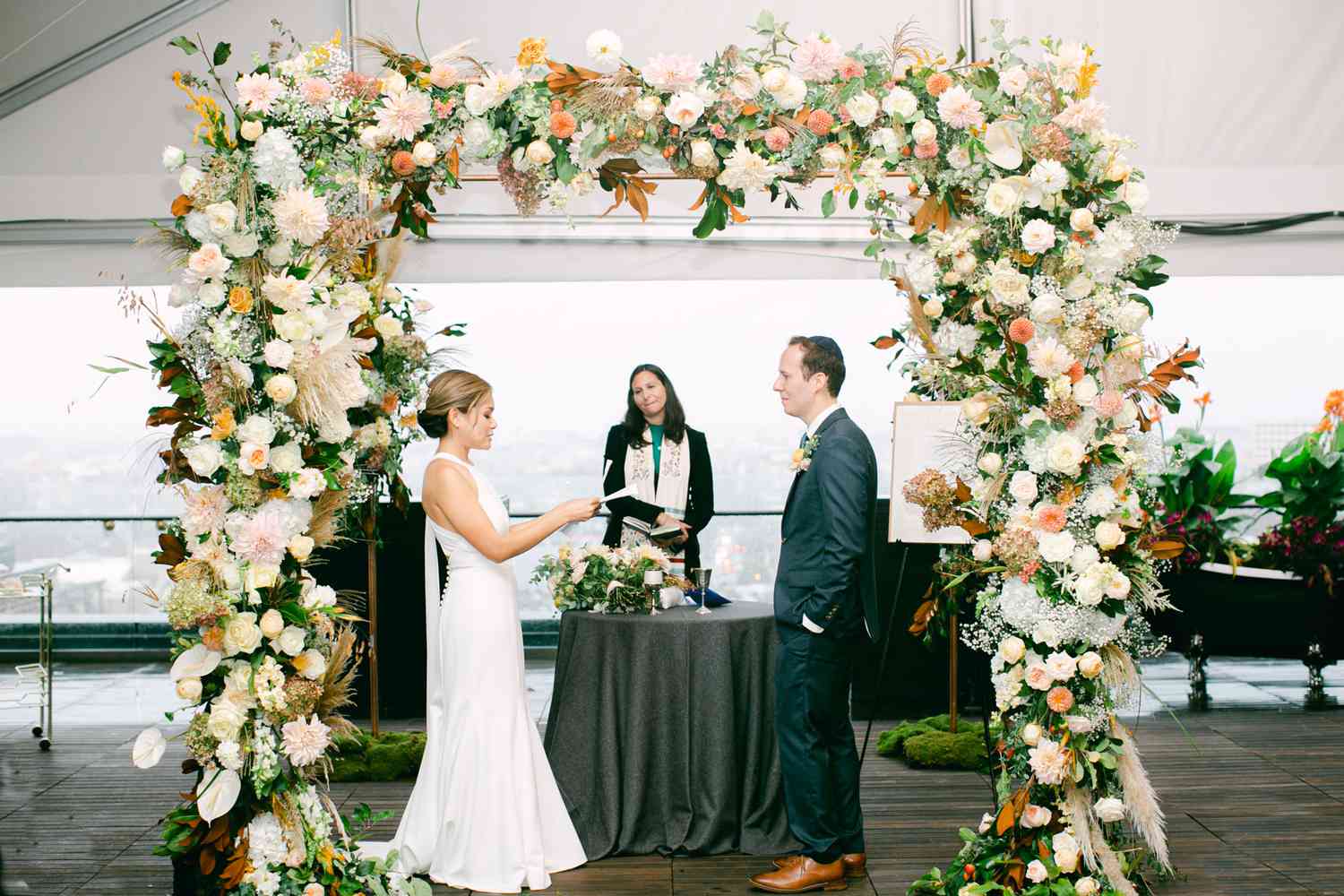bride and groom changing vows under floral arch