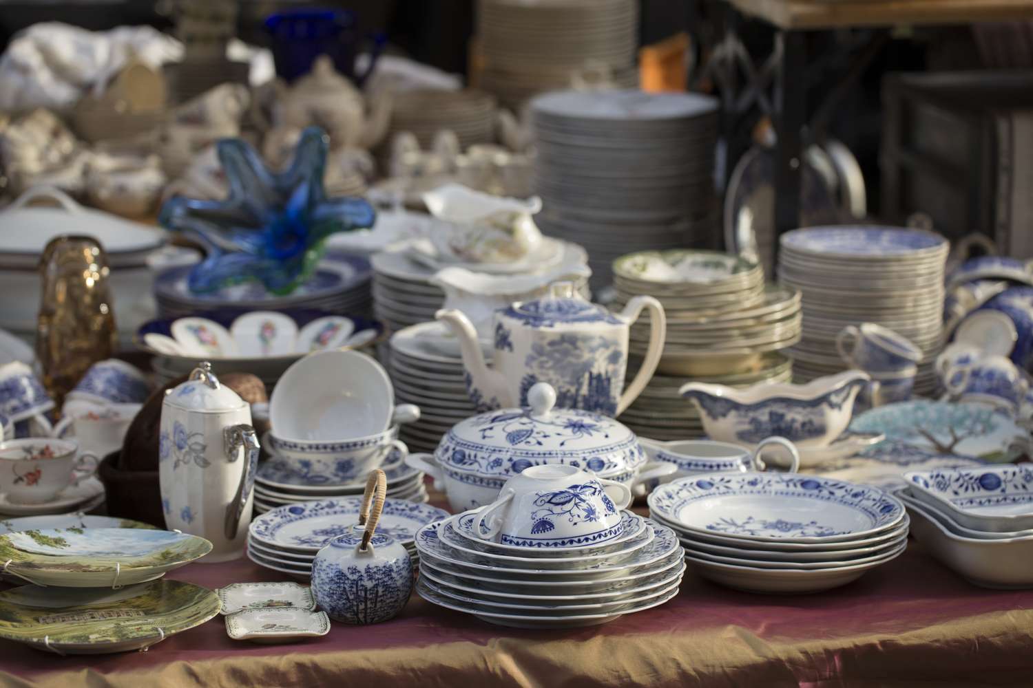 A collection of antique ceramic dishware displayed on a table at a market