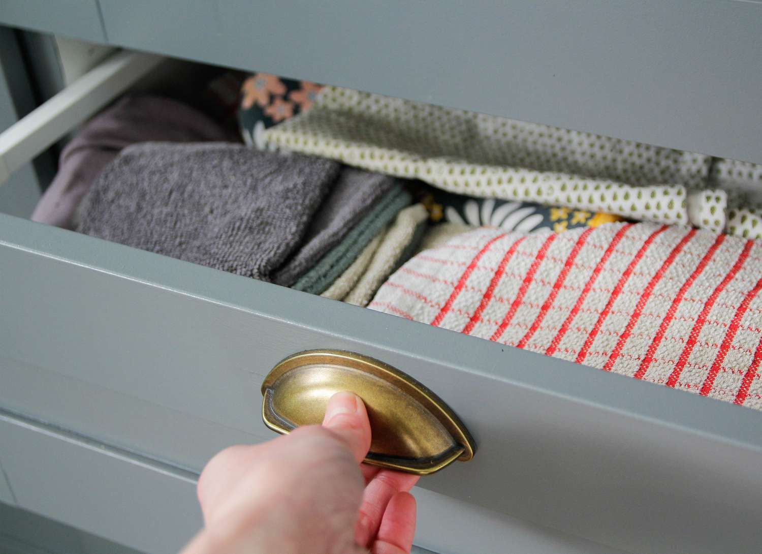 close up of a woman pulling a grey dresser drawer open