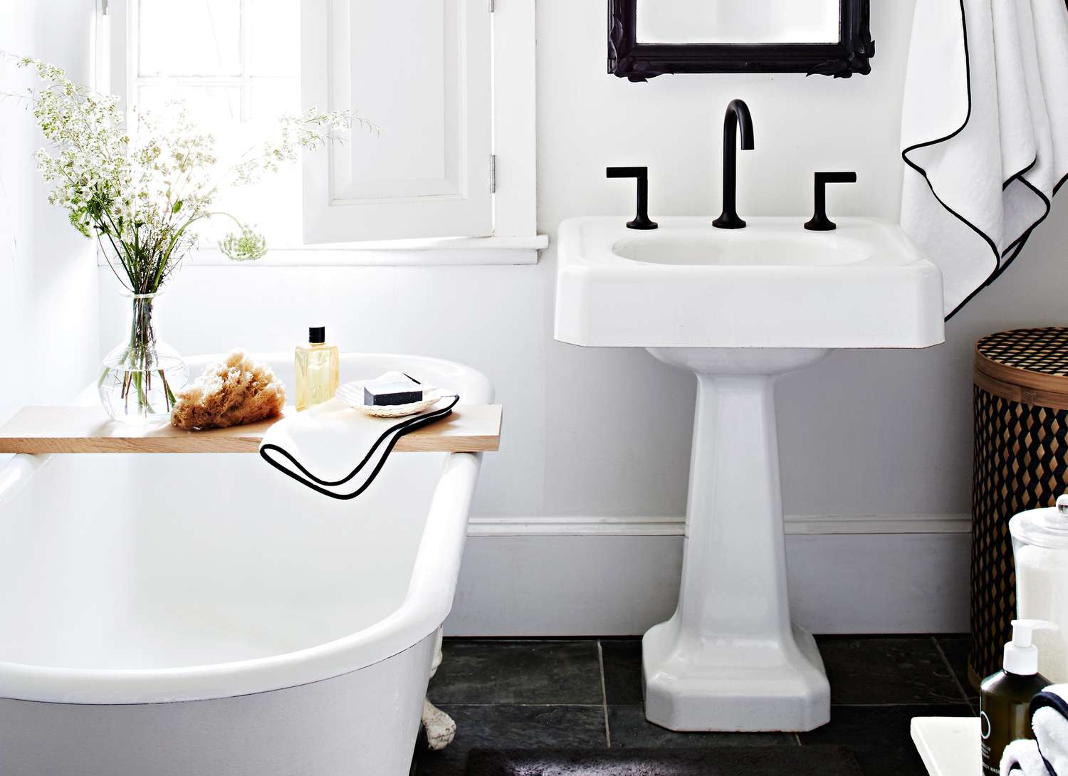 black and white bathroom with claw foot tub and pedestal sink