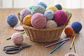 Colorful knitting yarns in a basket on a wooden background