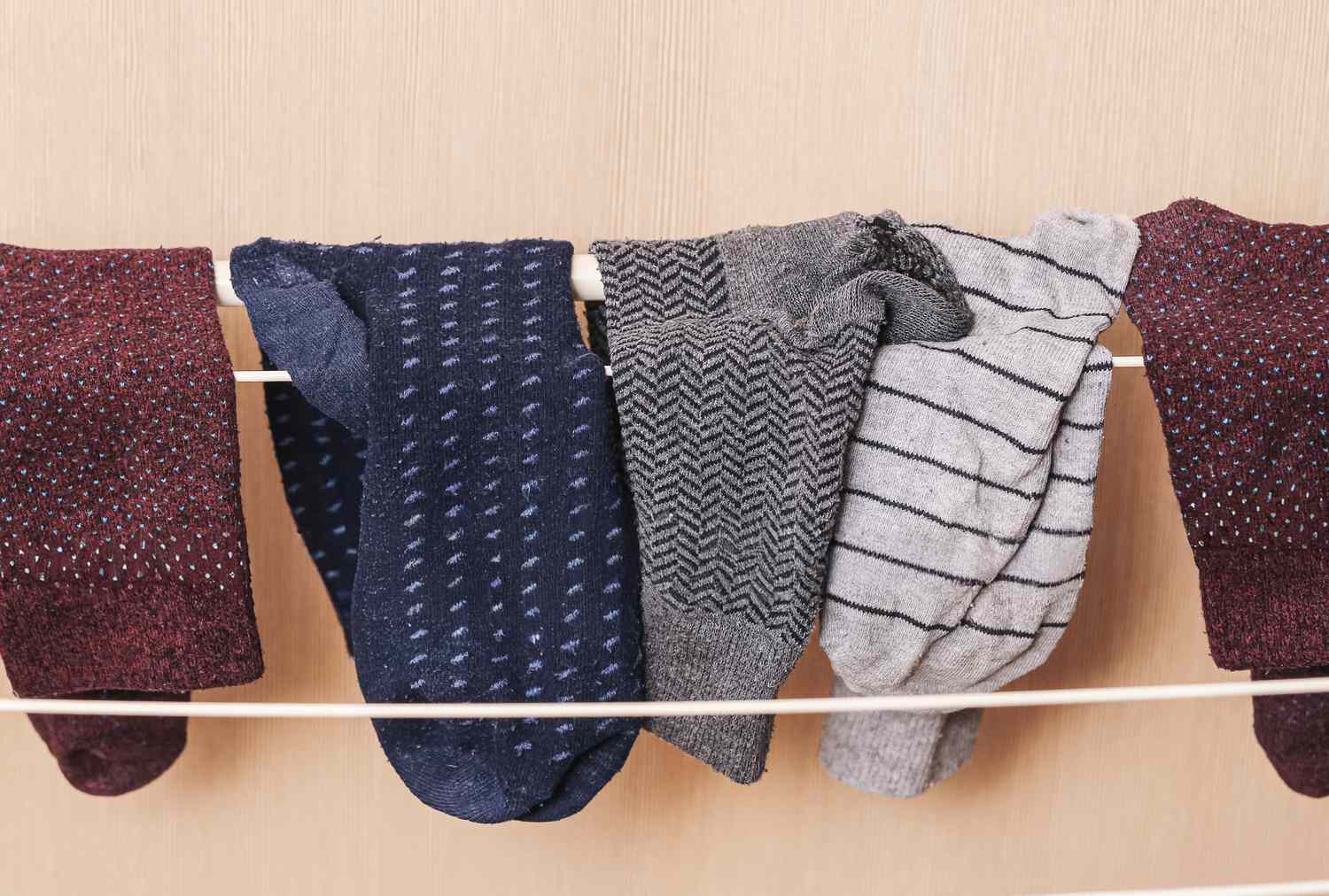 Several socks hanging on a drying rack indoors