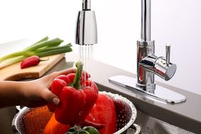 Woman washing peppers under a vegetable sprayer