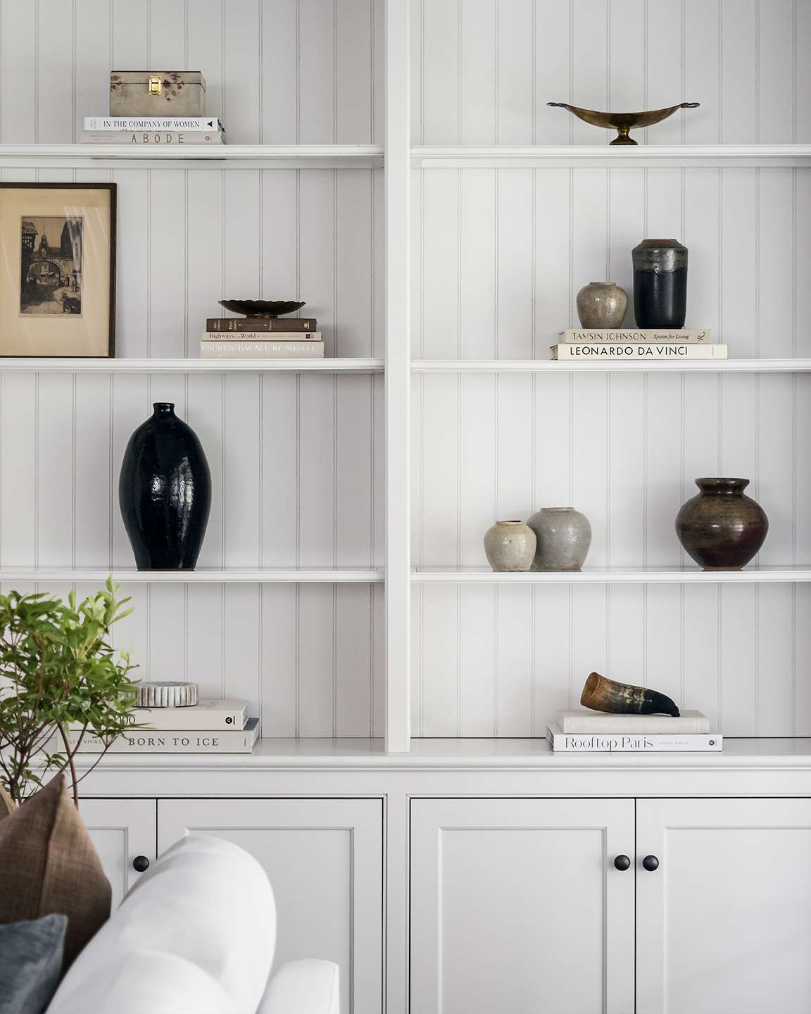 white tall shelves with bead board behind and objects