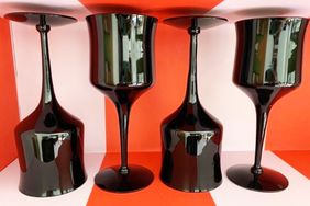 Four black goblets with reflective surfaces placed on a red and white background two are upside down and two are upright