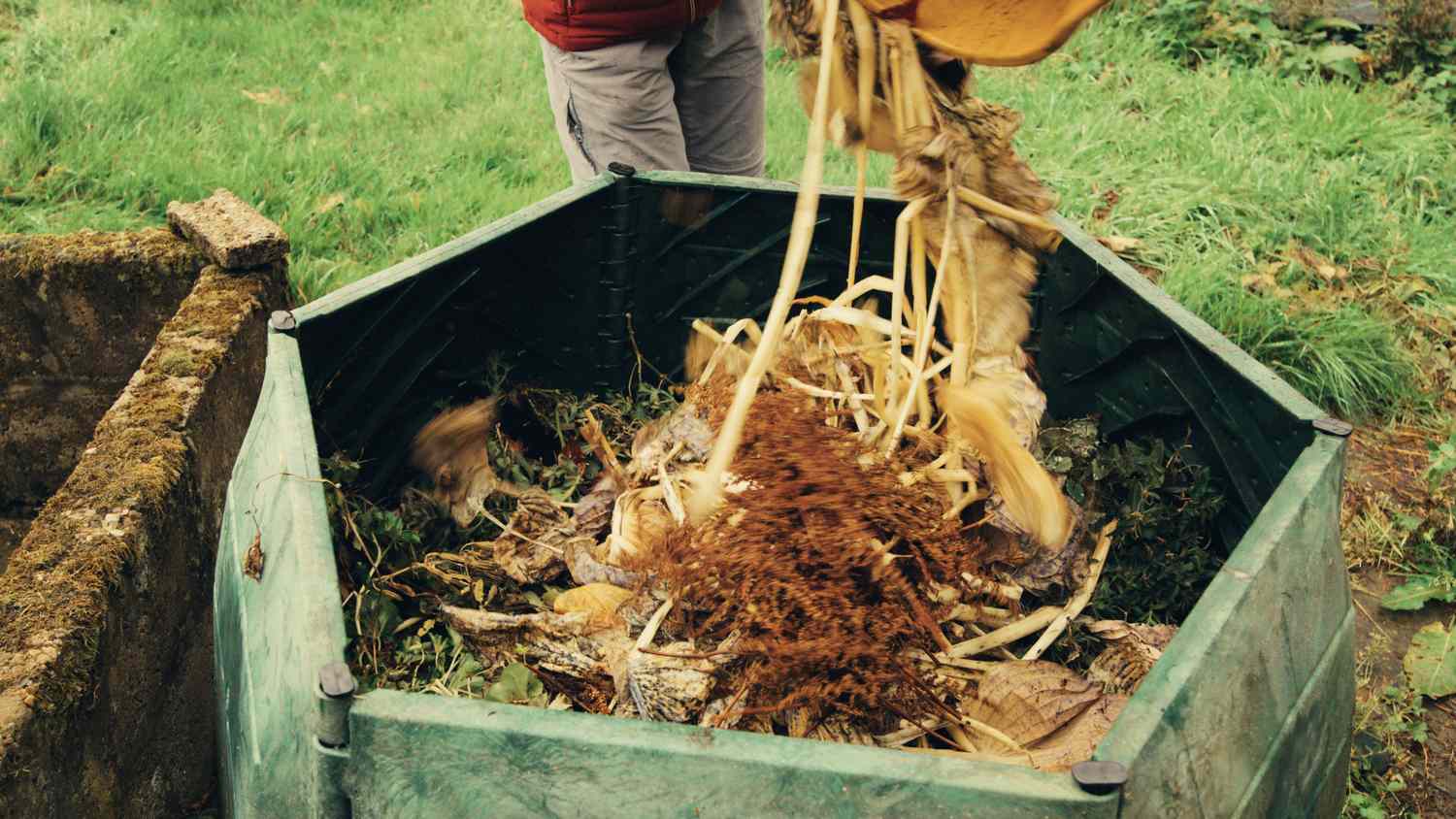 Person dumping garden waste into a compost bin