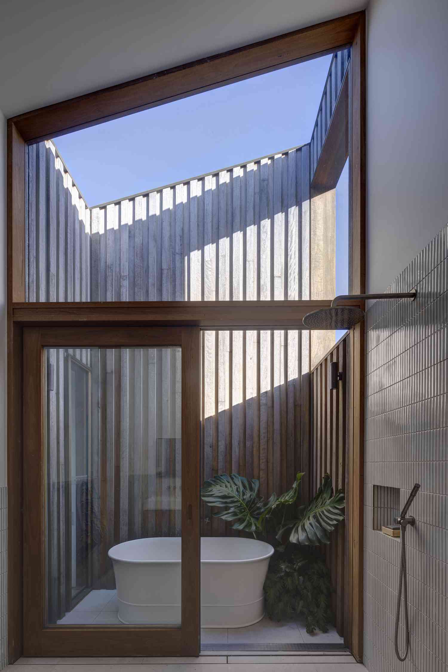 Outdoor meets indoor bathroom with full tub and shower.