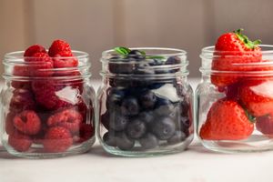 Glass jars of fresh berries on wooden table