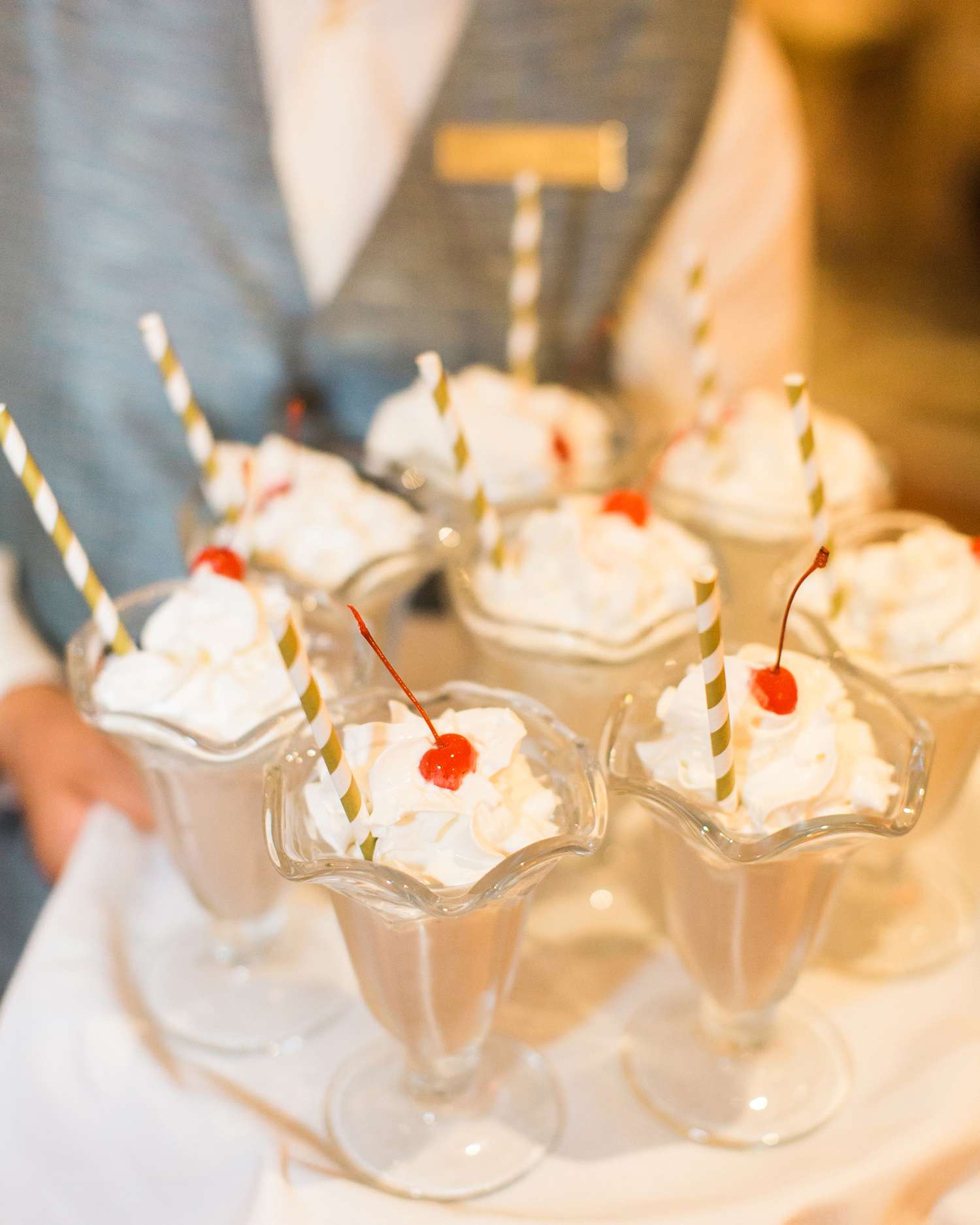 milkshakes topped with whipped cream and a cherry served on a tray