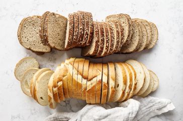 Two rows of sliced bread on a marble surface with a cloth to the side