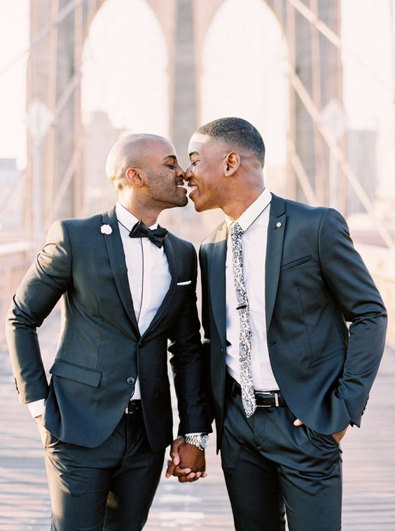grooms wearing black wedding suits with one wearing floral print tie