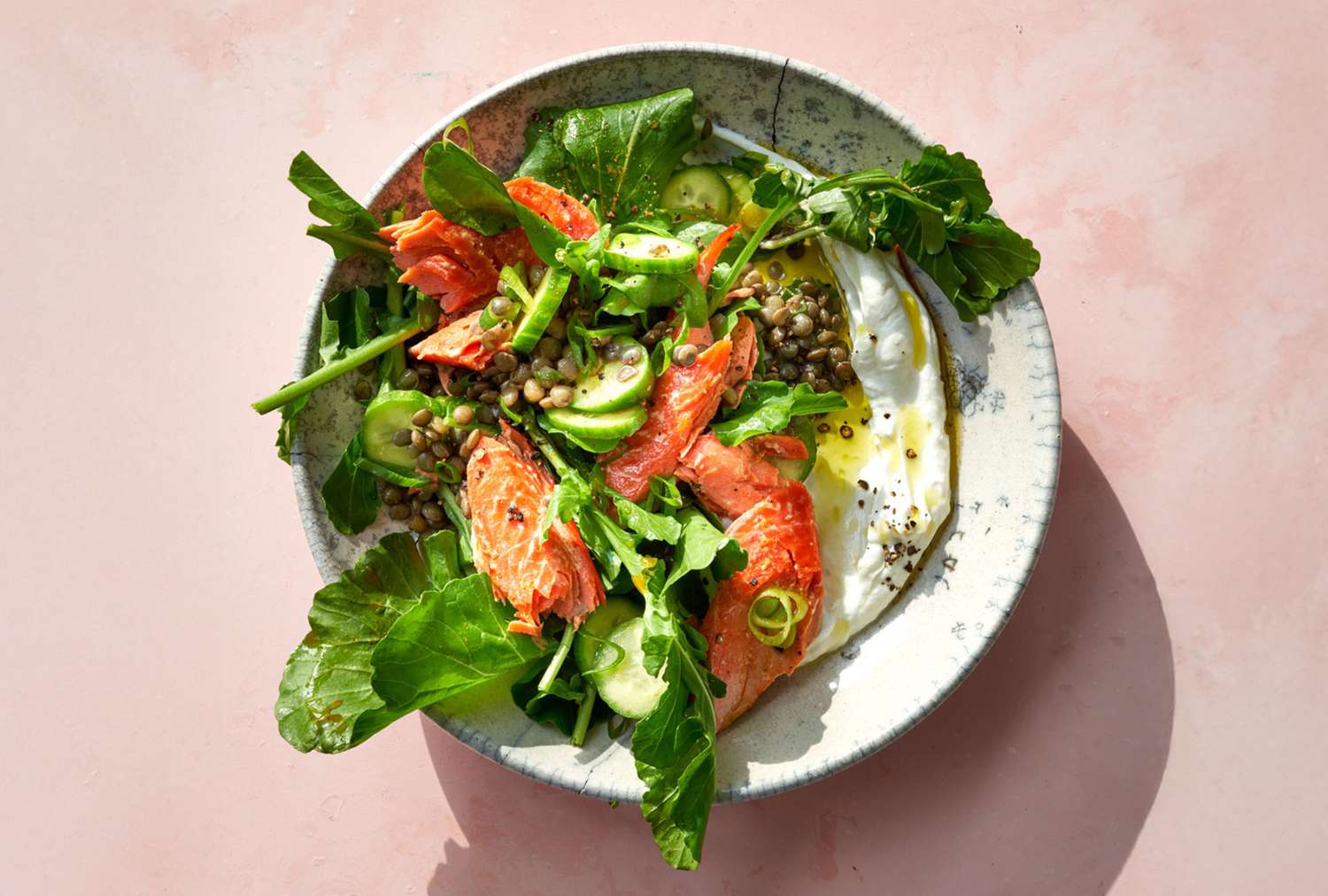 Salmon with lentil salad and greens on a plate