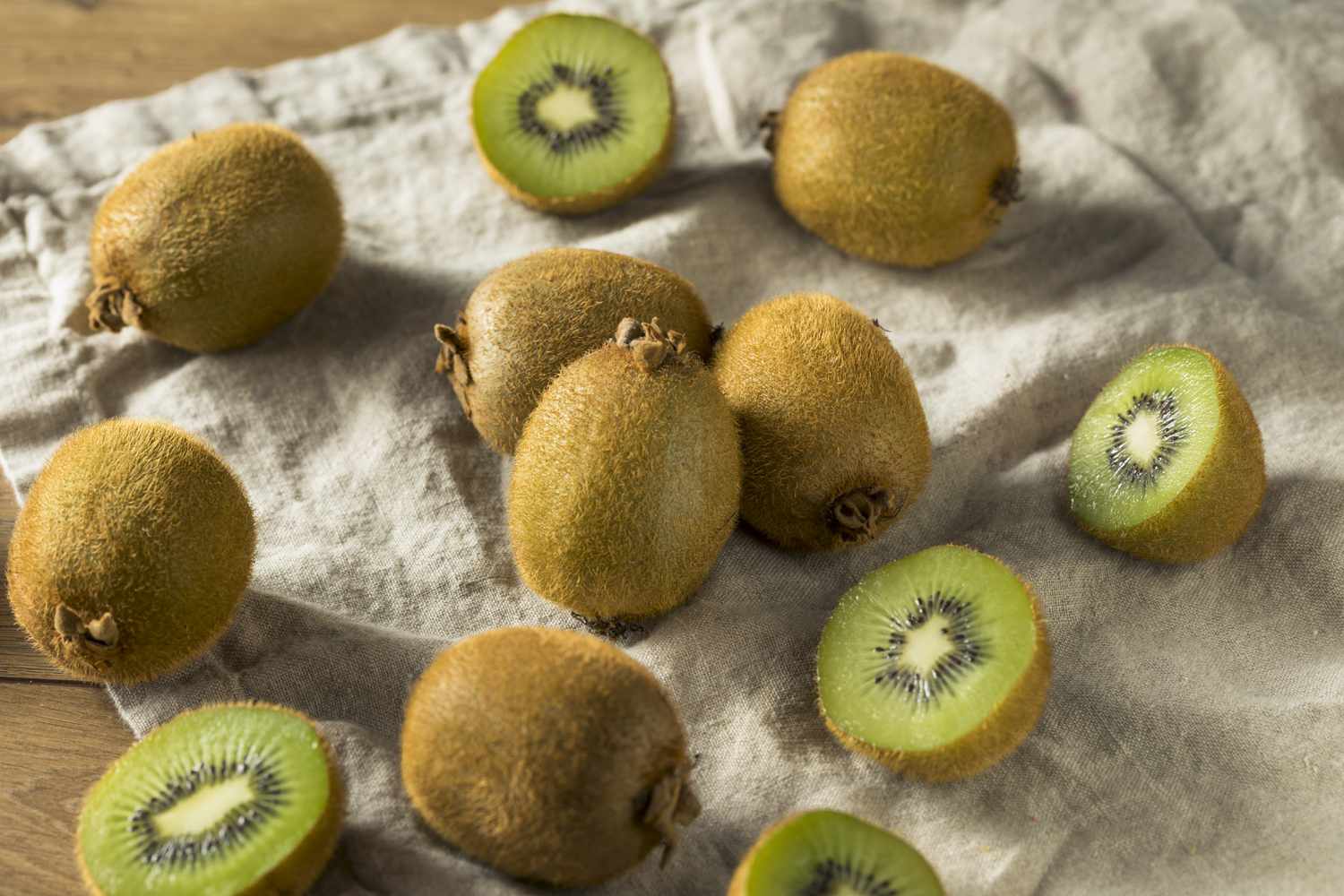 kiwi fruits, whole and halves, on linen cloth