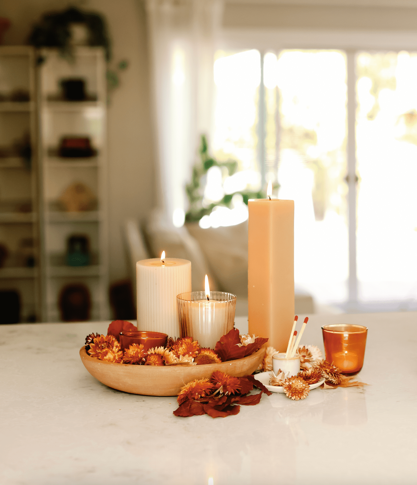 dried flowers in a bowl next to candles