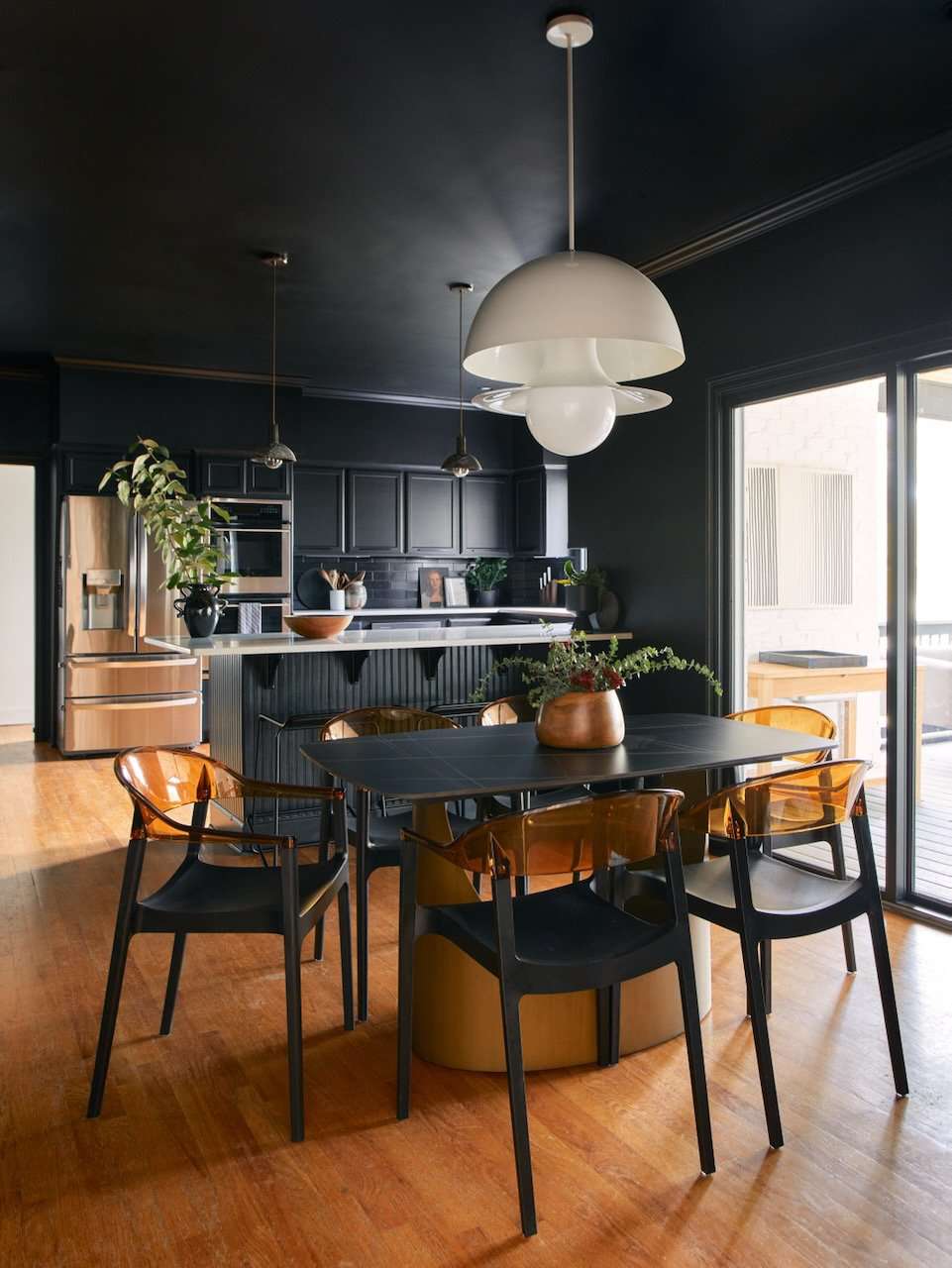 a black kitchen and dining room with white pendant lights