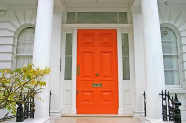 An entrance with a bright-colored door surrounded by architectural columns, part of a building