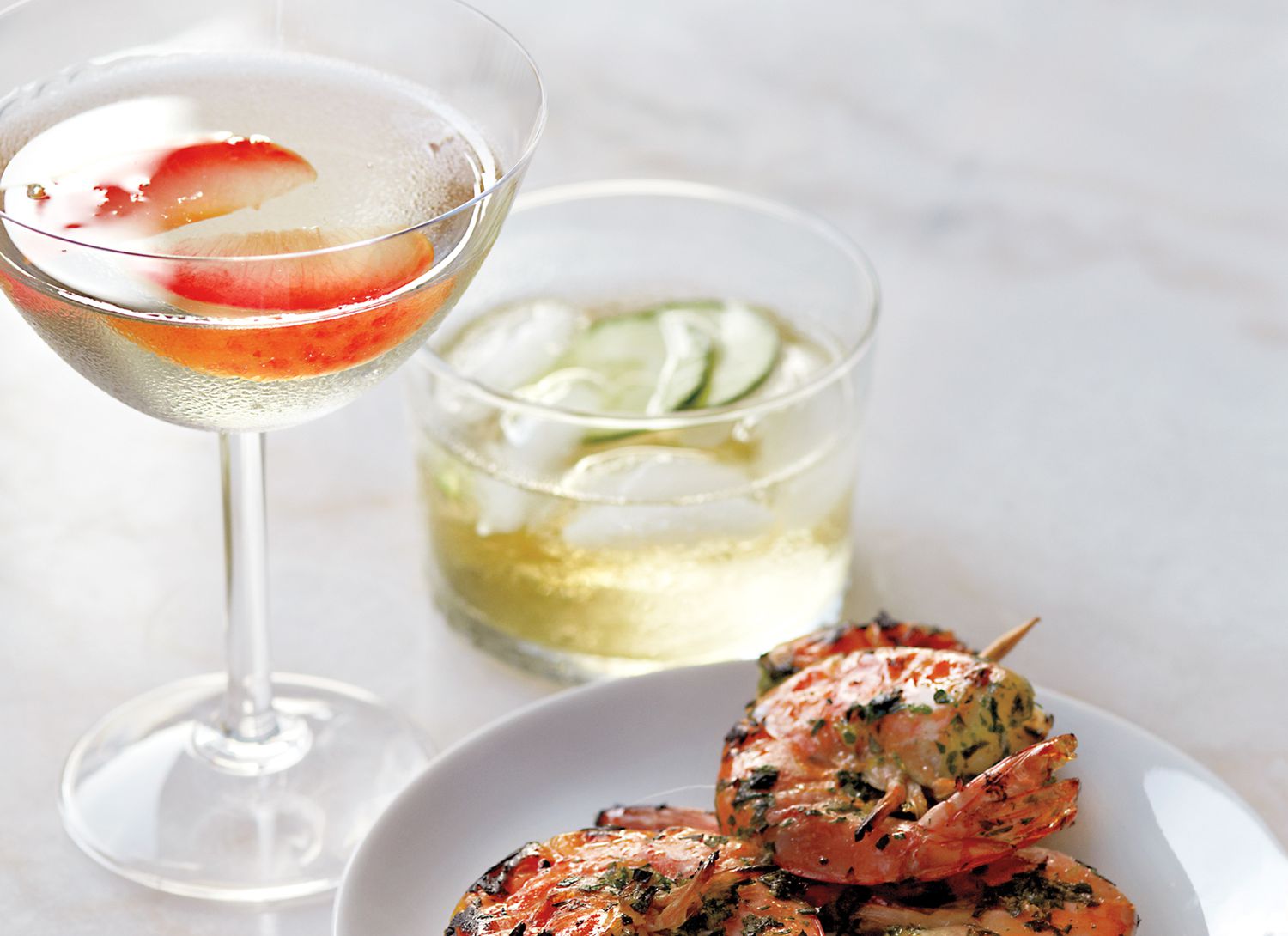 two aperitif cocktails with shrimp skewers on a marble surface