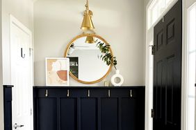 Entry way with gold accents, black wall, checkered rug