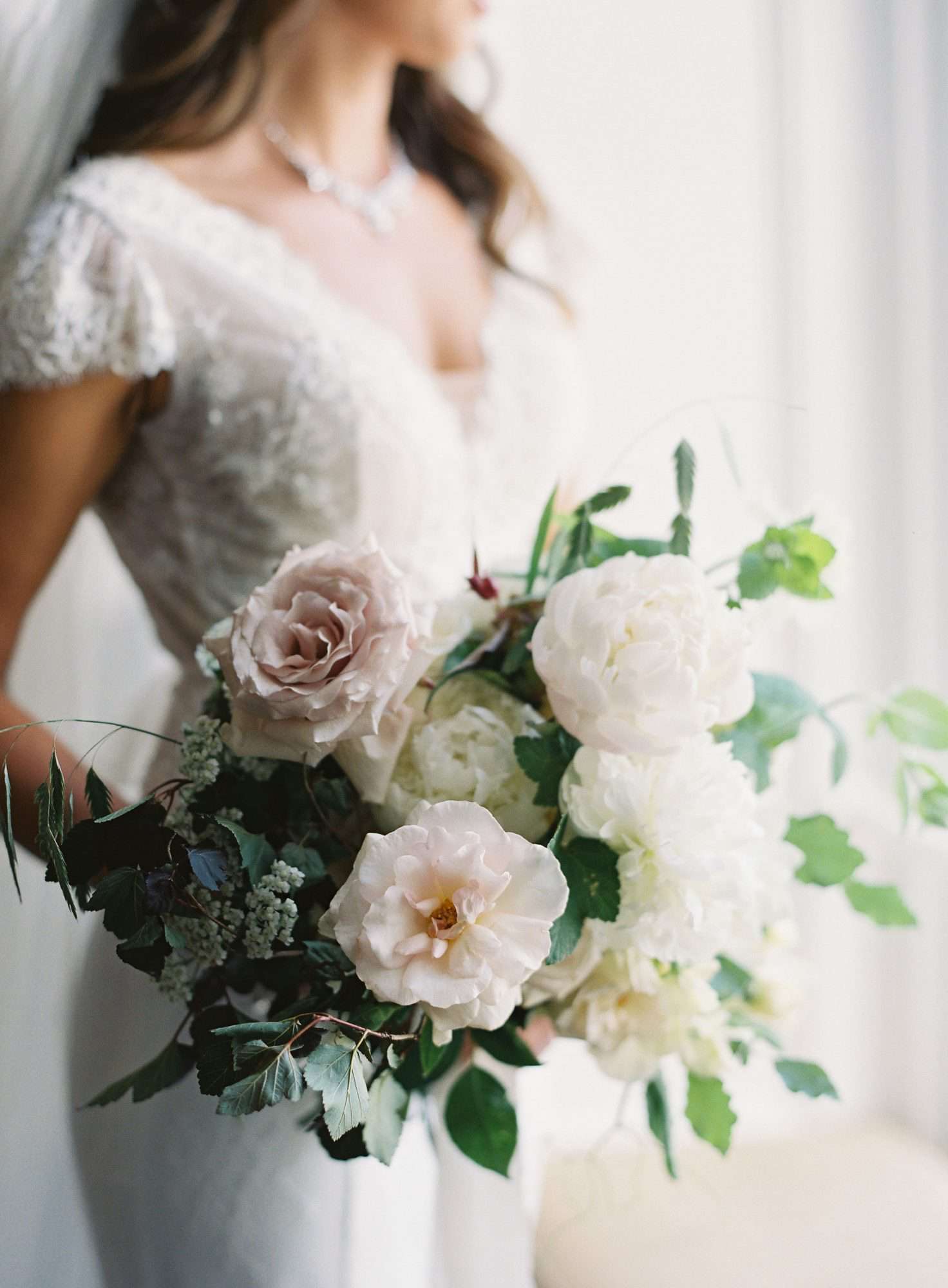 white, cream and very pale blush blooms with dark and light greenery wedding bouquet