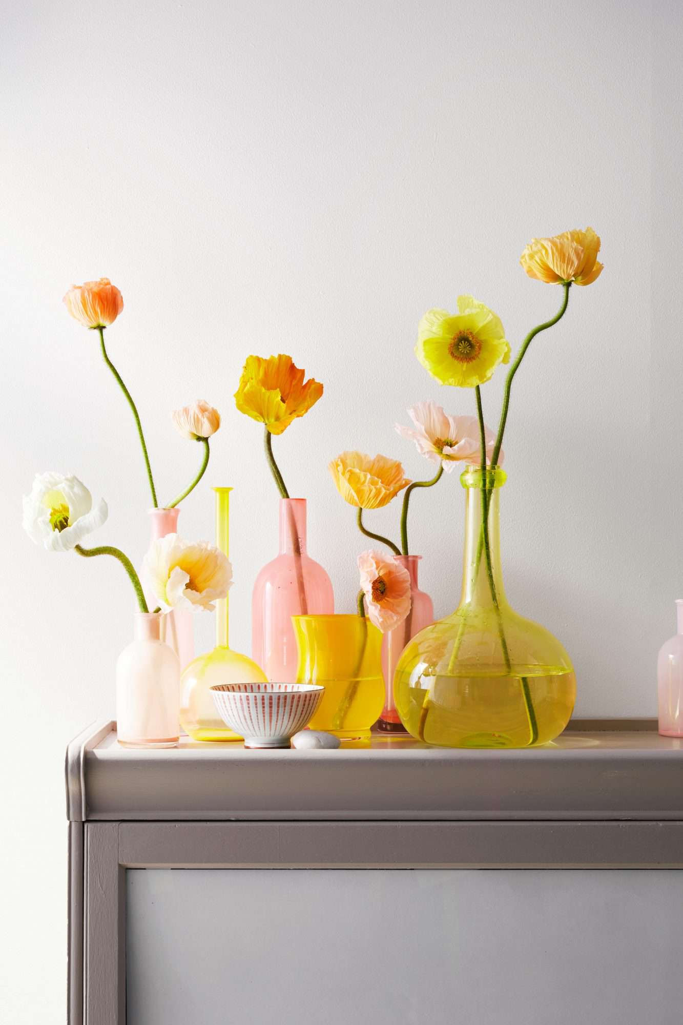 painted glass vases with flowers on gray stand