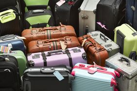 Multiple suitcases and luggage of varying sizes and styles stacked together viewed from above