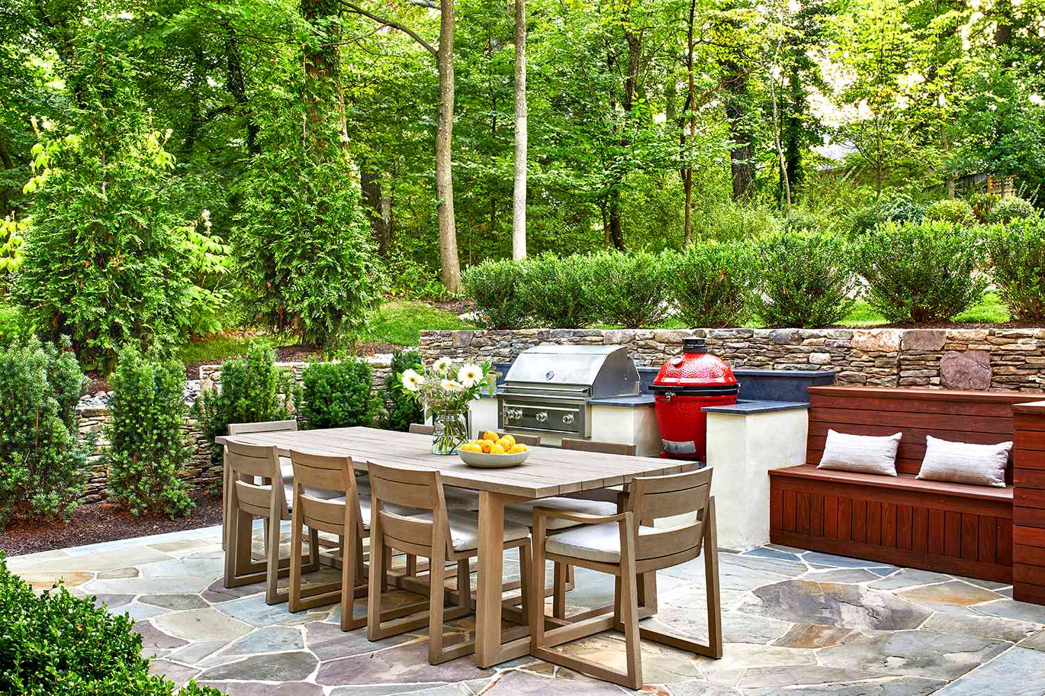 outdoor patio with dining area and grill in a wooded yard