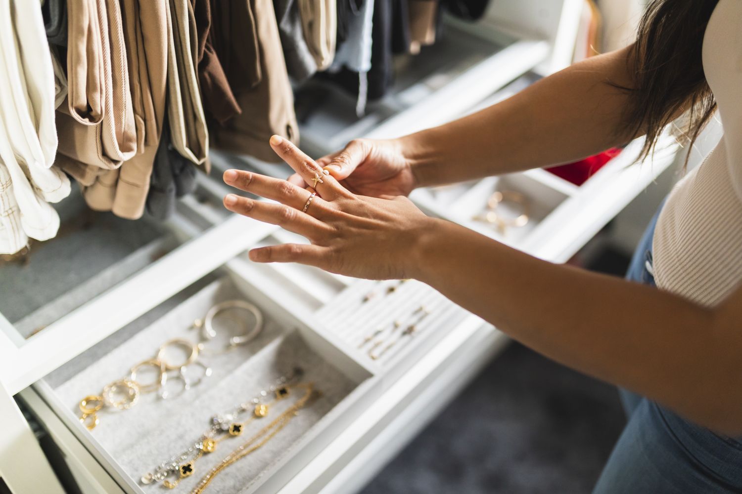 A person adjusting a ring on their finger in front of an open jewelry drawer