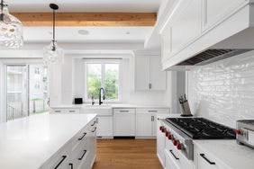 Modern kitchen with white cabinets island gas stove and pendant lighting