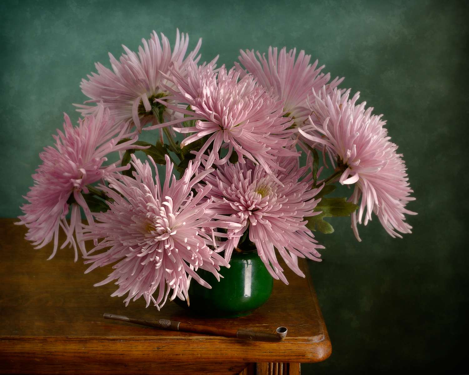 A bouquet of flowers in a green vase on a wooden table