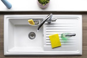 An overhead shot of a clean kitchen sink, a sponge and washing up liquid can be seen near by.