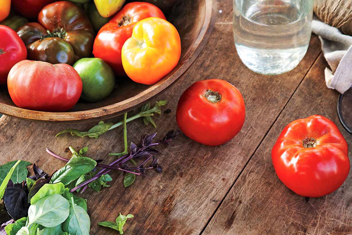 garden tomatoes and greens on wooden table