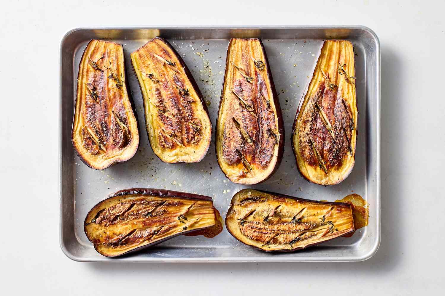 Halved roasted eggplants on a baking tray