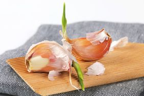 Two sprouted garlic cloves on a wooden surface