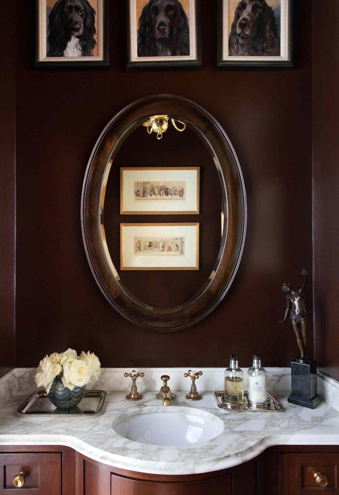 Brown painted bathroom with three framed photos of dogs