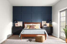 A bedroom with a wooden bed frame, blue paneled accent wall, bedside tables, and a window with natural light
