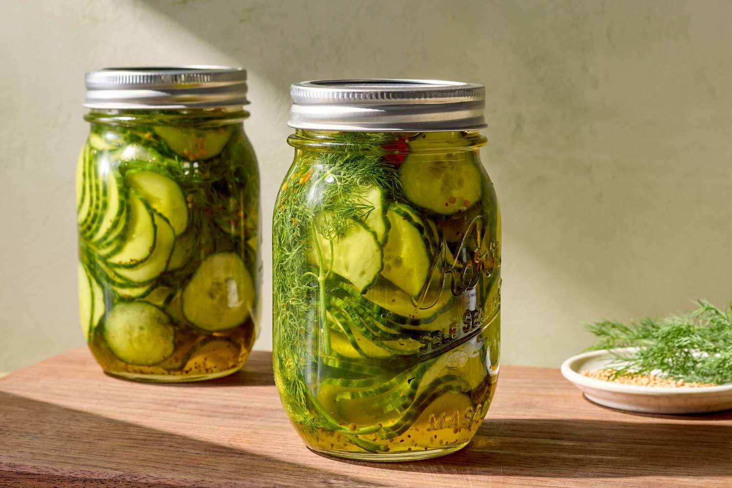 Jars of pickles with dill on a wooden surface