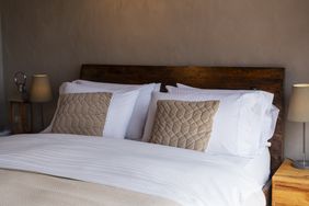 A neatly arranged bed with lightcolored bedding featuring two decorative pillows and wooden side tables with lamps