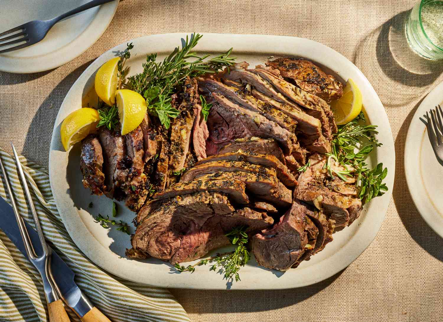 roast leg of lamb on a platter with garnishes