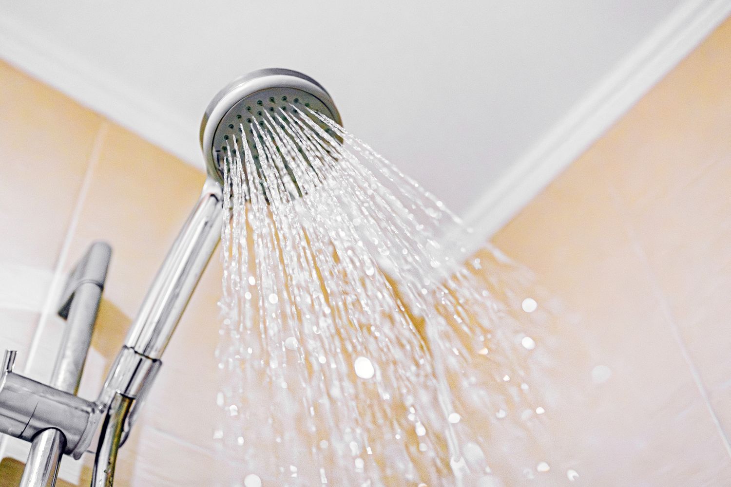 A showerhead with water streaming in a bathroom