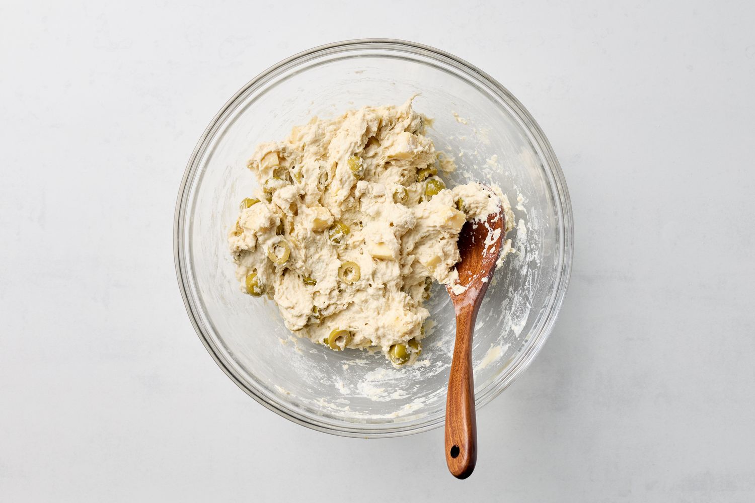 Bowl of olive and cheese bread batter with a wooden spoon